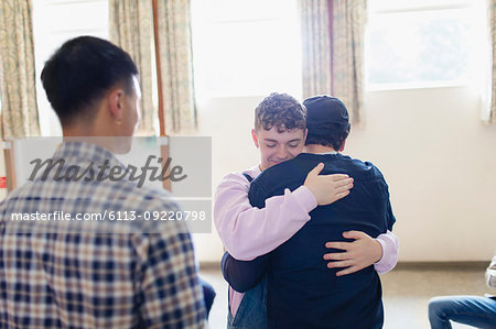 Men hugging in group therapy