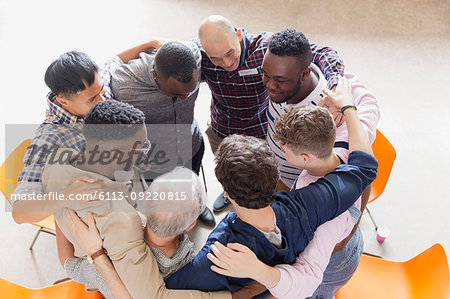 Men hugging in huddle in group therapy Men hugging in huddle in group therapy