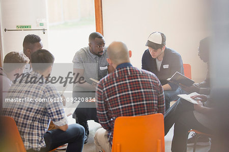 Men reading and discussing bible in circle in prayer group