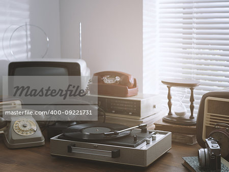 Vintage retro revival objects and second-hand appliances collection on a table: record player, television, radio and rotary dial telephones
