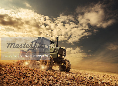 Farmer in the fields driving a tractor on fertile soil during a sunny summer day