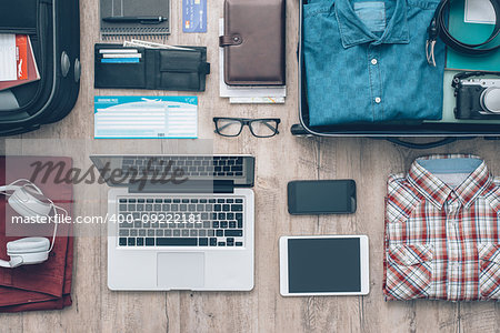 Travel equipment on a desktop: clothing, wallet, laptop, tablet, smartphone and personal accessories, travel and vacations concept