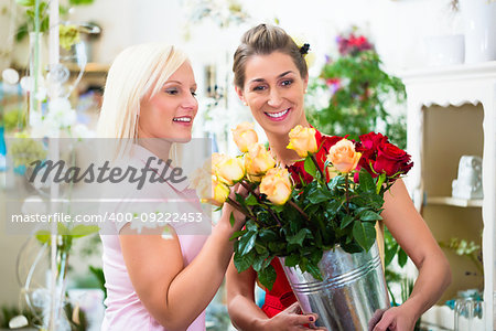 Two women looking at bouquet of yellow roses in flower shop
