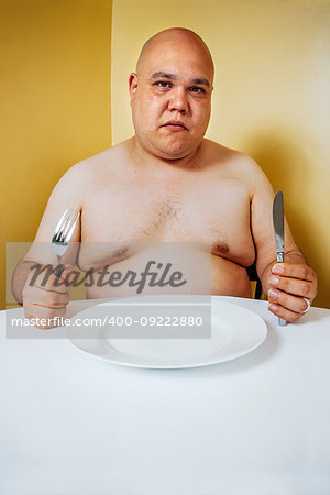 Photo of a large topless man waiting impatiently at a table for food.