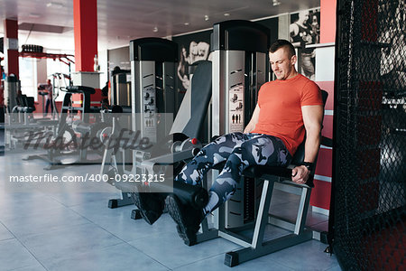 Fit man training legs on leg press machine in the gym. Sport activities