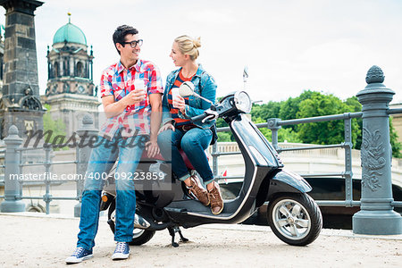 Tourists, woman and man, on scooter trip in Berlin taking a rest on the Museum Island