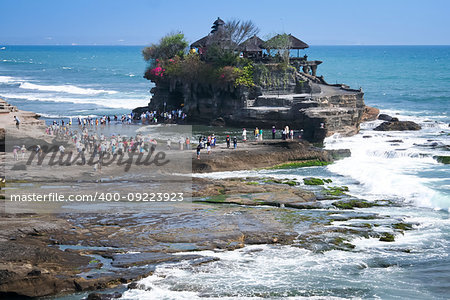 tourists crossing to the landmark sea temple of tanah lot on the coast of bali indonesia