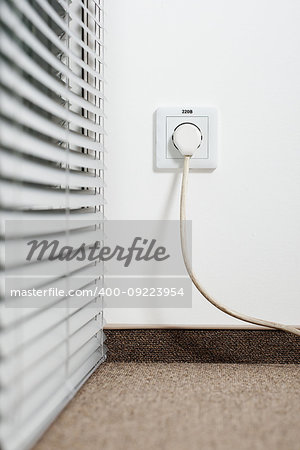 socket in the plug with a plug with a wire on a white wall