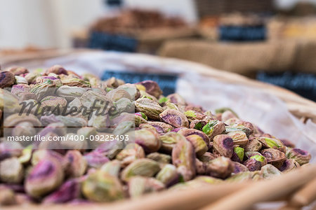 Background of basket of pistachios without shells, captured on street market, selective focus