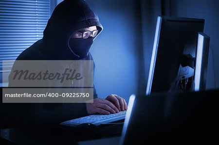 Hacker in front of his computer. Dark face