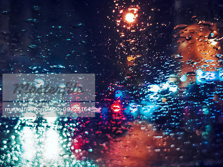 Blurred light traffic lights bokeh with rain drops on glass a night