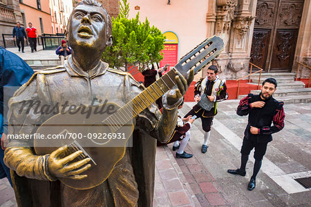 Musicians in costume next to a bronze statue of a musician in front of the Guanajuato Basilica in Guanajuato City, Guanajuato, Mexico