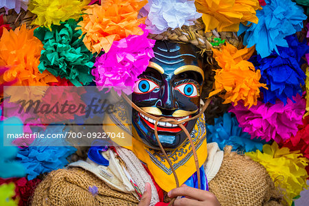 Close-up of indigenous tribal dancer wearing mask and colurful flowers at a St Michael Archangel Festival parade in San Miguel de Allende, Mexico