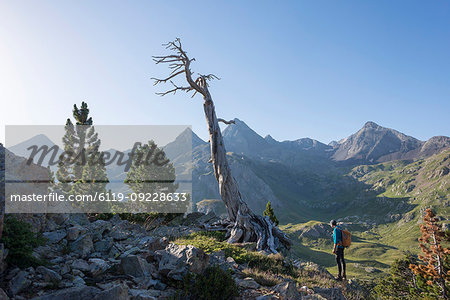 A walker takes in a view of the Pyrenees from near Refugio Respomuso along the GR11 long distance trekking path, Huesca, Spain, Europe