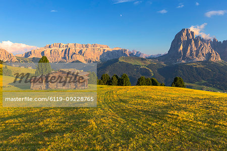Last rays of sun on traditional hut with view on Sassolungo and Sella Group, Gardena Valley, South Tyrol, Dolomites, Italy, Europe