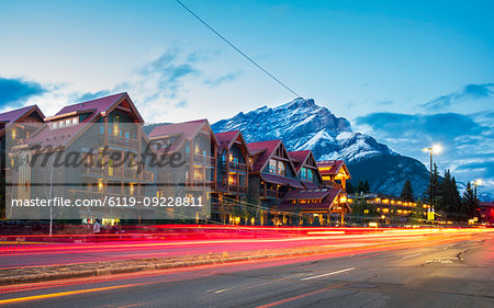 Trail lights on Banff Avenue and mountains in background at dusk, Banff, Banff National Park, Alberta, Canada, North America