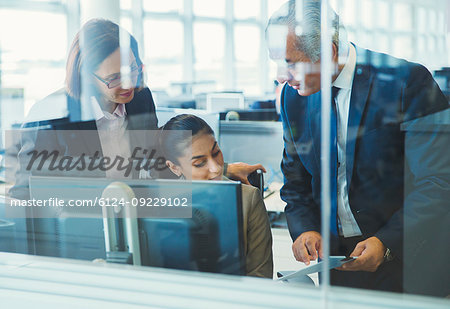 Business people discussing paperwork at computer in office