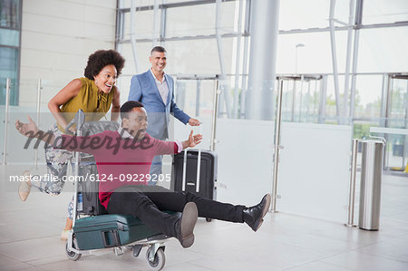 Playful couple running with luggage cart in airport