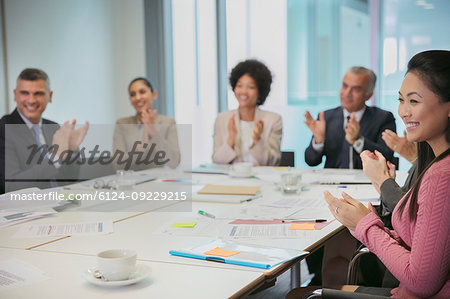Smiling business people clapping in conference room meeting