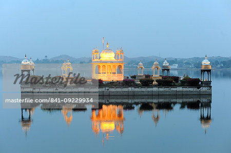 Vijay Raj Rajeshwar temple, reflected in the Gaibsagar Lake, built in 1923, lighting up at dusk for evening prayers, Dungarpur, Rajasthan, India, Asia