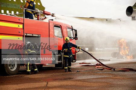 Firemen training, spraying water from fire engine at mock airplane engine