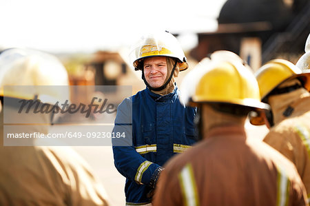 Firemen training, firemen listening to supervisor at training facility, over shoulder view