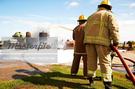 Firemen training, team of firemen spraying firefighting foam at training facility