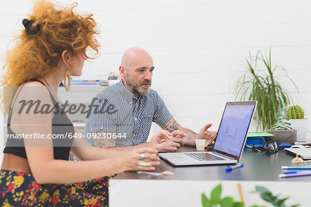 Businessman and woman looking at laptop in office