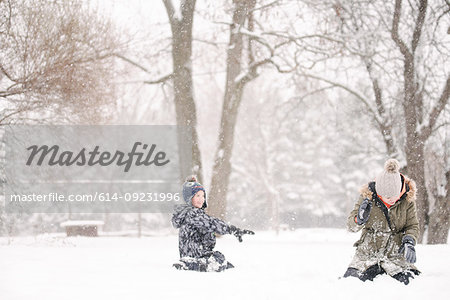 Boy throwing snowball at sister