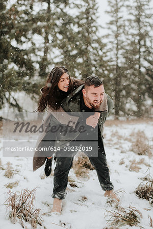 Couple playing piggyback in snowy landscape, Georgetown, Canada