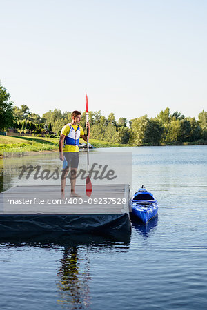 Young Professional Kayaker Getting Ready for Morning Kayak Training on the River. Sport and Active Lifestyle Concept