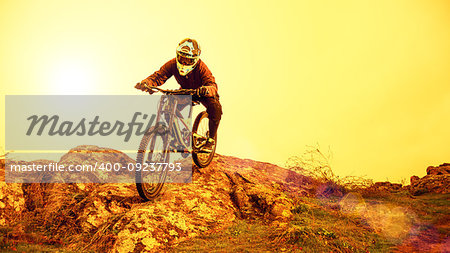 Professional Cyclist Riding the Mountain Bike Down the Rocky Hill. Extreme Sport and Enduro Biking Concept.