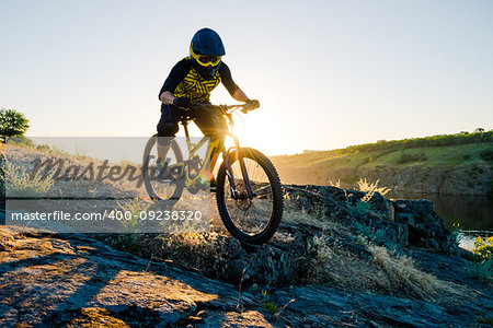 Professional Cyclist Riding the Downhill Mountain Bike on the Summer Rocky Trail at the Evening. Extreme Sport and Enduro Cycling Concept.