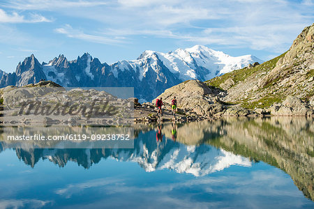 Hikers and the summit of Mont Blanc reflected in Lac Blanc on the Tour du Mont Blanc trekking route in the French Alps, Haute Savoie, Auvergne-Rhone-Alpes, France, Europe