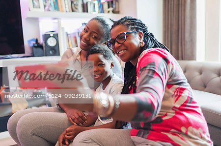Multi-generation family taking selfie with camera phone in living room