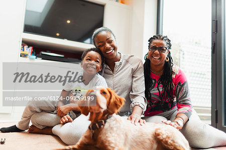 Portrait happy multi-generation family with dog on living room floor