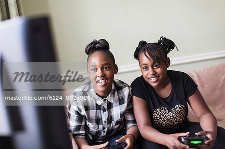 Tween girl friends playing video game in living room