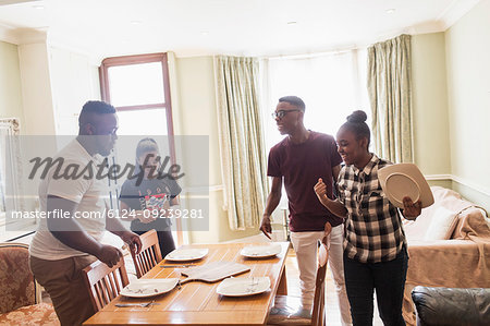 Teenage siblings setting dining room table