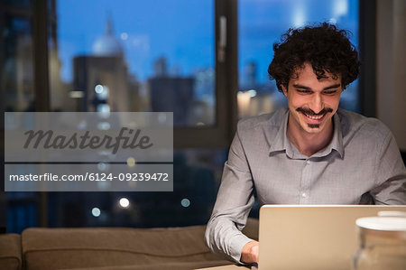 Man using laptop in urban apartment at night