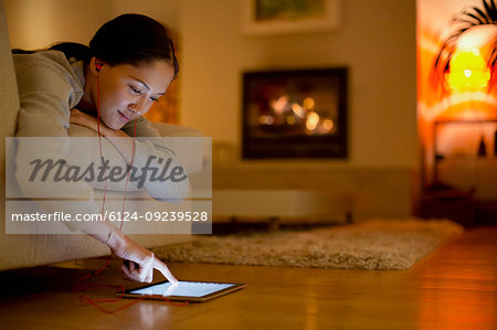 Young woman with headphones using digital tablet in living room