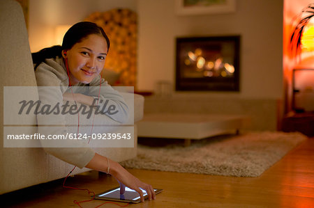 Portrait smiling young woman listening to music with headphones and digital tablet