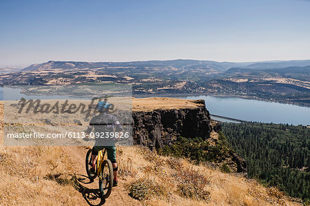 Man mountain biking, enjoying Columbia River view from cliff, Hood River, Oregon, USA