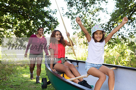 Happy mother and daughters pushing canoe in woods