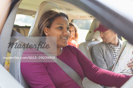 Smiling woman driving car with family on road trip