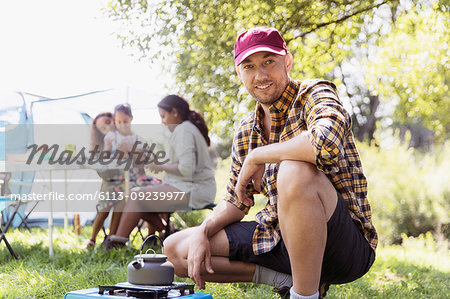 Portrait confident man heating teapot on camping stove at sunny campsite