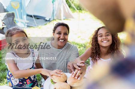 Father serving barbecue hamburgers to eager family at campsite