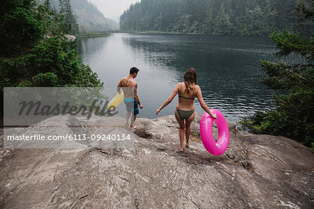 Young couple with inflatable rings at remote lakeside, Squamish, British Columbia, Canada