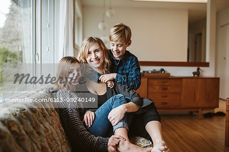 Portrait happy mother and children cuddling on living room sofa