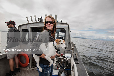 Portrait smiling woman with dog on fishing boat