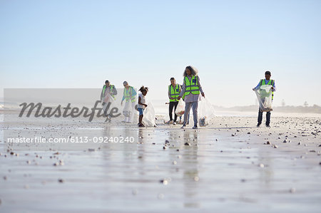 Volunteers cleaning up litter on sunny wet sand beach